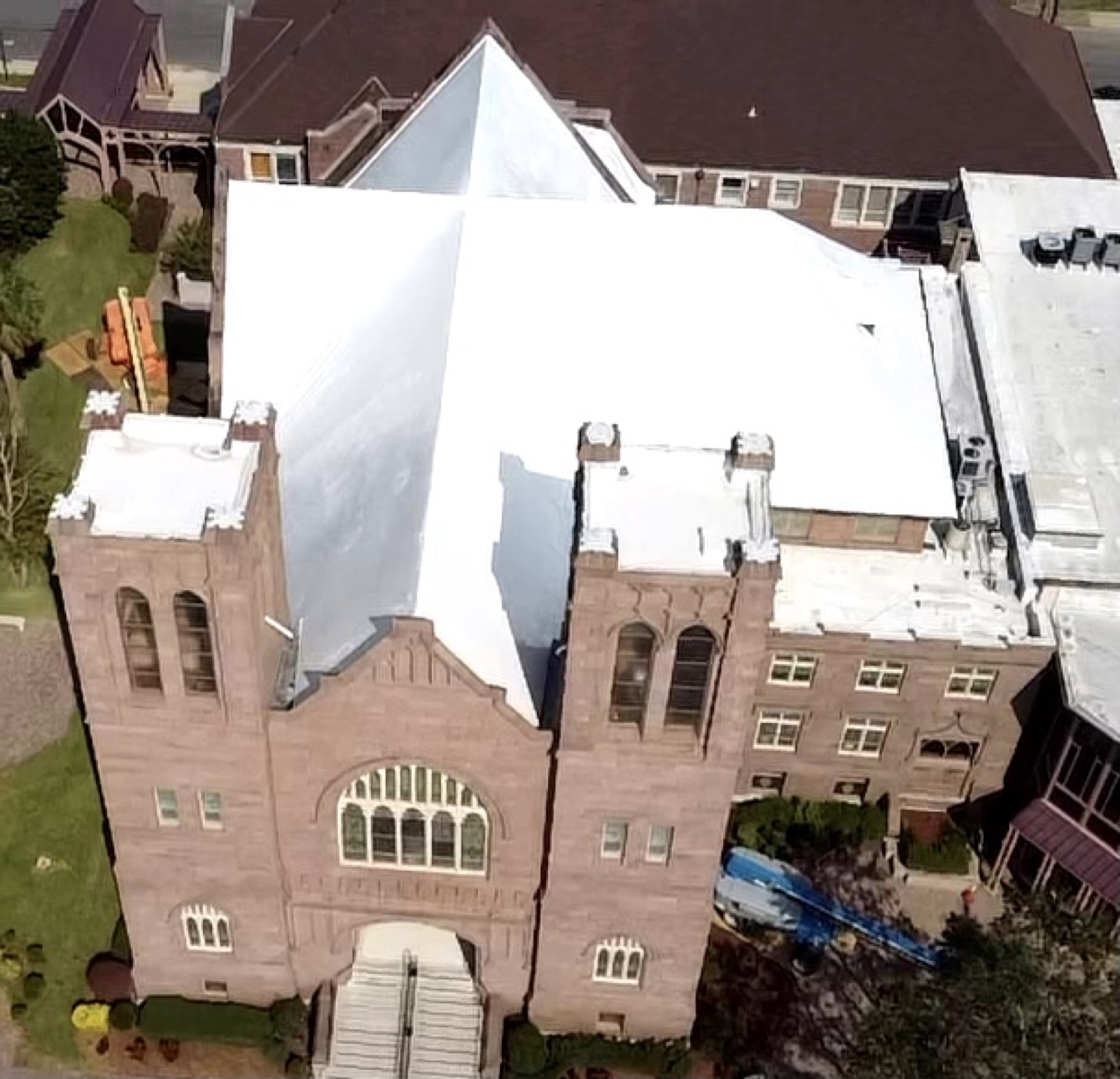 Historic brick church and tower under white stretch wrap roof protection