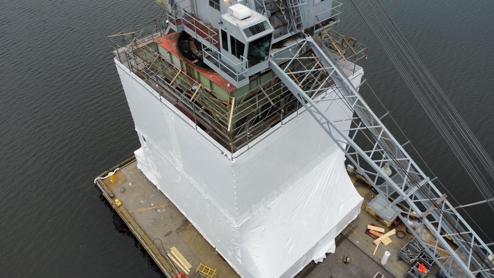 White membrane being installed around the scaffold with its upper section still open